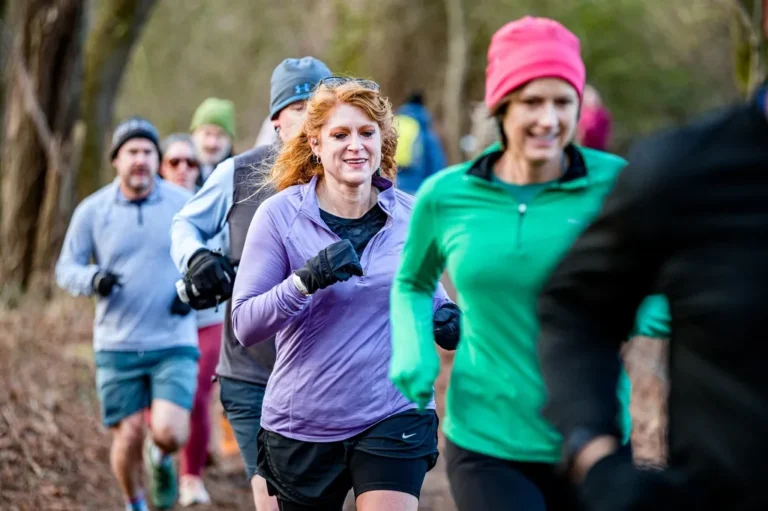 Group of adults jogging together on a wooded trail