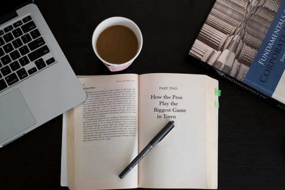 Laptop, open book and coffee on a desk for online learning