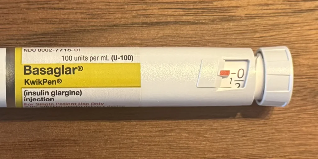 Close-up of a prefilled insulin pen showing the label, dose window and dose knob on a wooden table