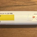 Close-up of a prefilled insulin pen showing the label, dose window and dose knob on a wooden table
