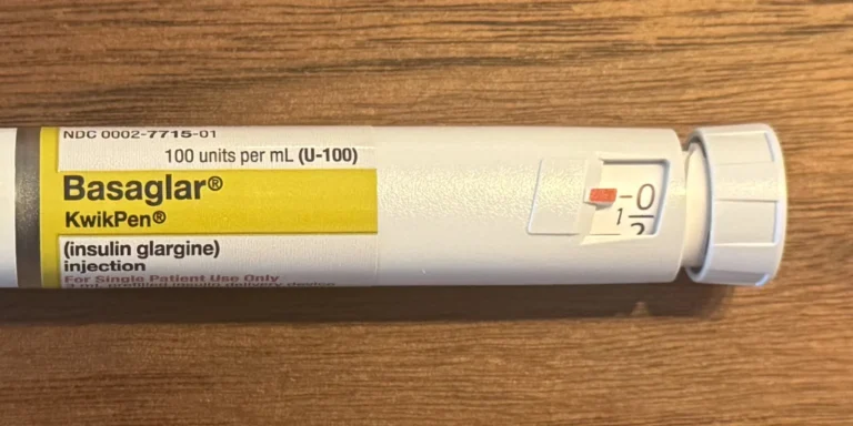 Close-up of a prefilled insulin pen showing the label, dose window and dose knob on a wooden table
