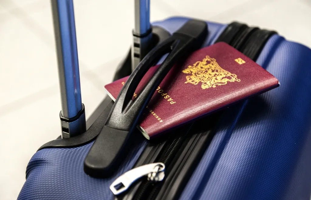 Passport resting on the handle of a blue suitcase ready for travel
